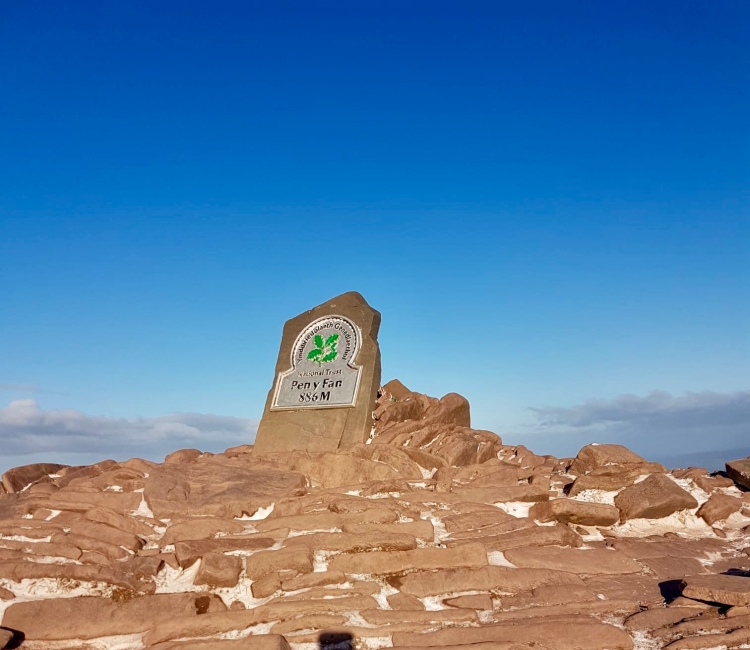 National Trust sign at summit of Pen Y Fan Wales under blue skies
